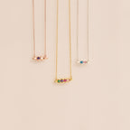 The Horizontal Pod Birthstone Necklace is shown with various colored chains on a beige background—ideal for anyone wanting a personalized jewelry accent or a custom birthstone necklace.