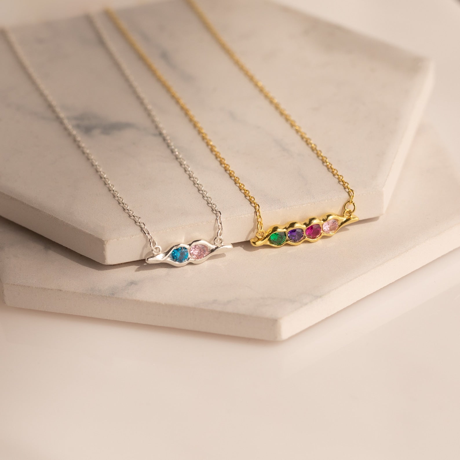 The Horizontal Pod Birthstone Necklace features custom birthstones in silver or gold, beautifully displayed on hexagonal marble slabs.