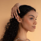 Woman with long curly hair poses sideways, hand on head, wearing elegant Old English Name Earrings—a perfect custom gift—against a beige background.