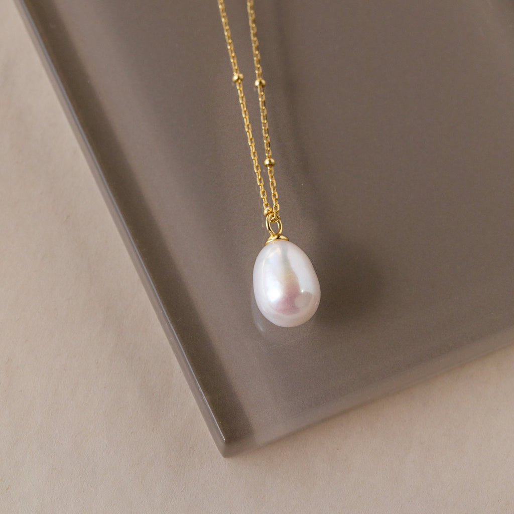 The Ariel Pearl Necklace features a gold chain with a single white pearl pendant, making it the perfect choice for elegant bridal or timeless bridesmaid jewelry.