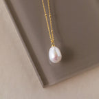 The Ariel Pearl Necklace features a gold chain with a single white pearl pendant, making it the perfect choice for elegant bridal or timeless bridesmaid jewelry.