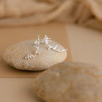 The Hallie Name Earrings, displayed on smooth stones against a beige fabric background, make a perfect custom gift or stylish personalized accessory for any occasion.