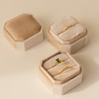 Three elegant 2 Slot Velvet Ring Boxes display gold rings—one with a green gemstone—on a neutral surface.