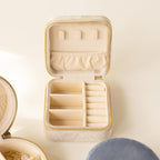 The Square Velvet Jewelry Case is a small, beige velvet box with compartments and a zipper, shown open on a light surface.