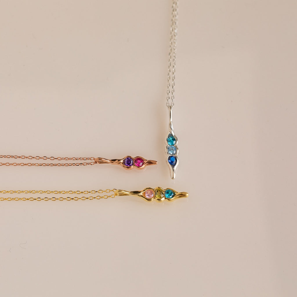 The Vertical Pod Birthstone Necklace features vibrant gemstones on gold, rose gold, and silver chains—ideal for fans of personalized jewelry.