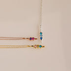 The Vertical Pod Birthstone Necklace features vibrant gemstones on gold, rose gold, and silver chains—ideal for fans of personalized jewelry.