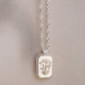 The Ribbed Flower Tag Necklace features a rectangular, flower-engraved pendant and vintage-inspired style—ideal for adding everyday charm.