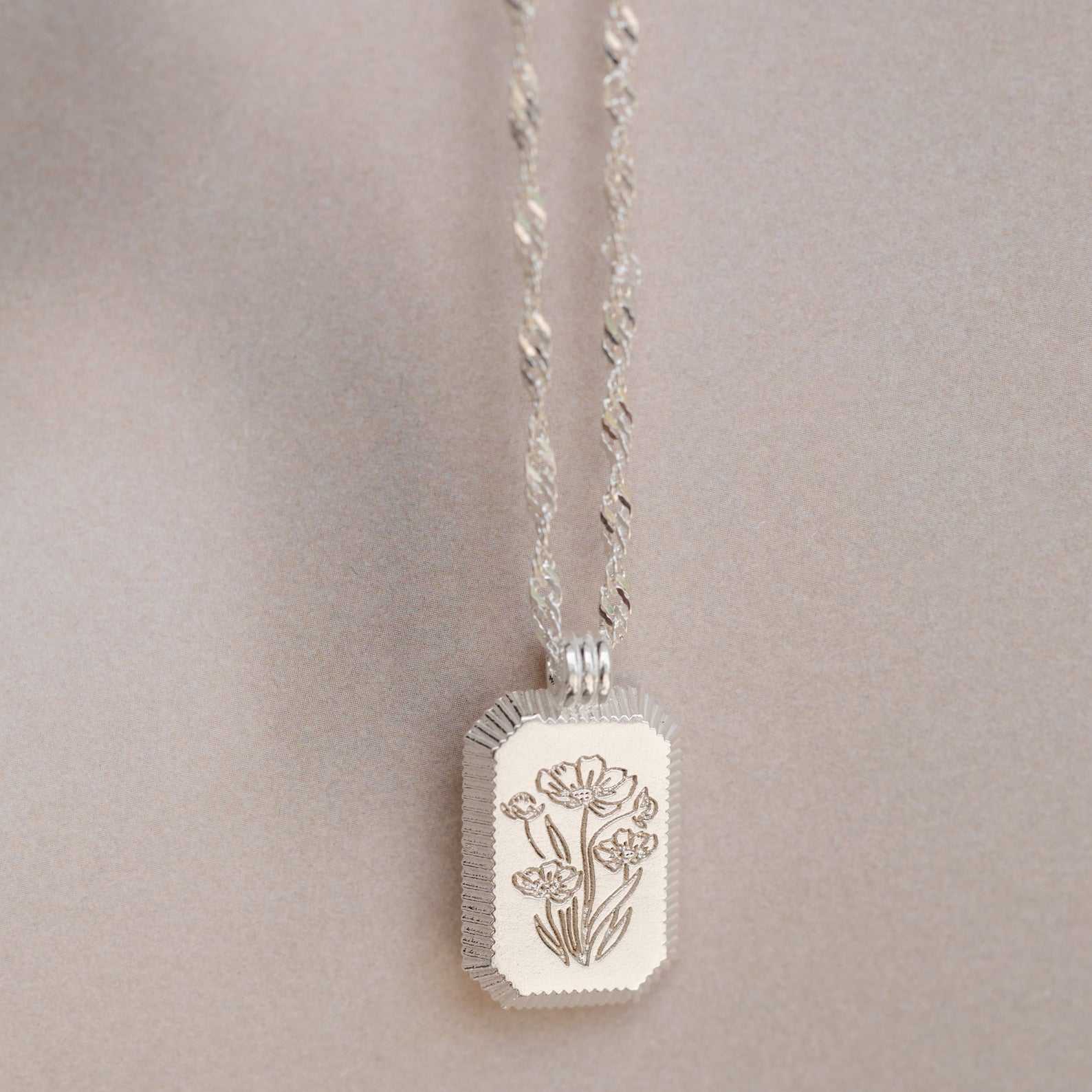 The Ribbed Flower Tag Necklace features a rectangular, flower-engraved pendant and vintage-inspired style—ideal for adding everyday charm.