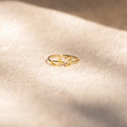 The Hallie Duo Initial Ring, personalized with the letters A S, rests on a soft beige surface in gentle sunlight—the perfect gift for mothers who love meaningful jewelry.