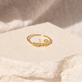 The Hallie Duo Initial Ring, featuring "AS," rests on a textured, light-colored stone surface—a stylish personalized jewelry piece and an ideal gift for moms.
