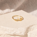 The Hallie Duo Initial Ring, featuring "AS," rests on a textured, light-colored stone surface—a stylish personalized jewelry piece and an ideal gift for moms.