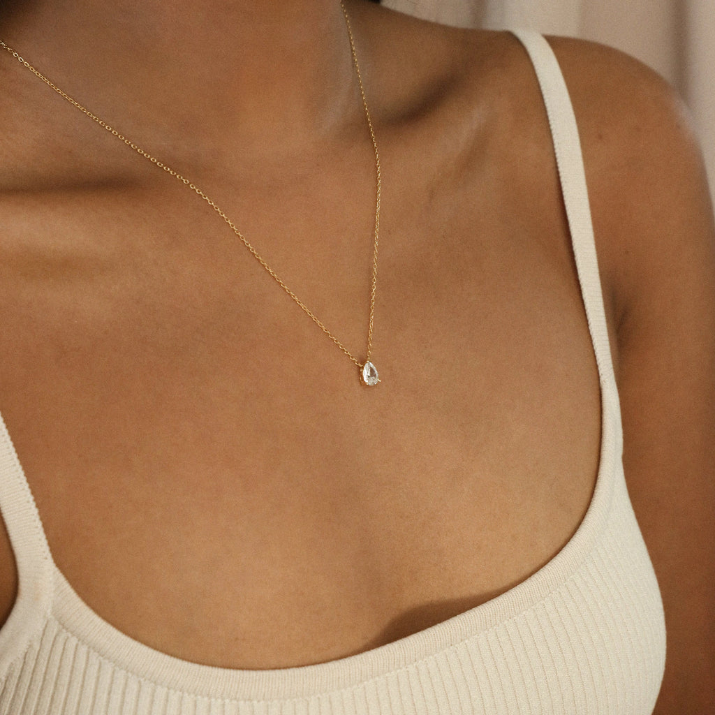 Rae Diamond Necklace with small oval pendant on delicate 18K gold chain on model's neckline.