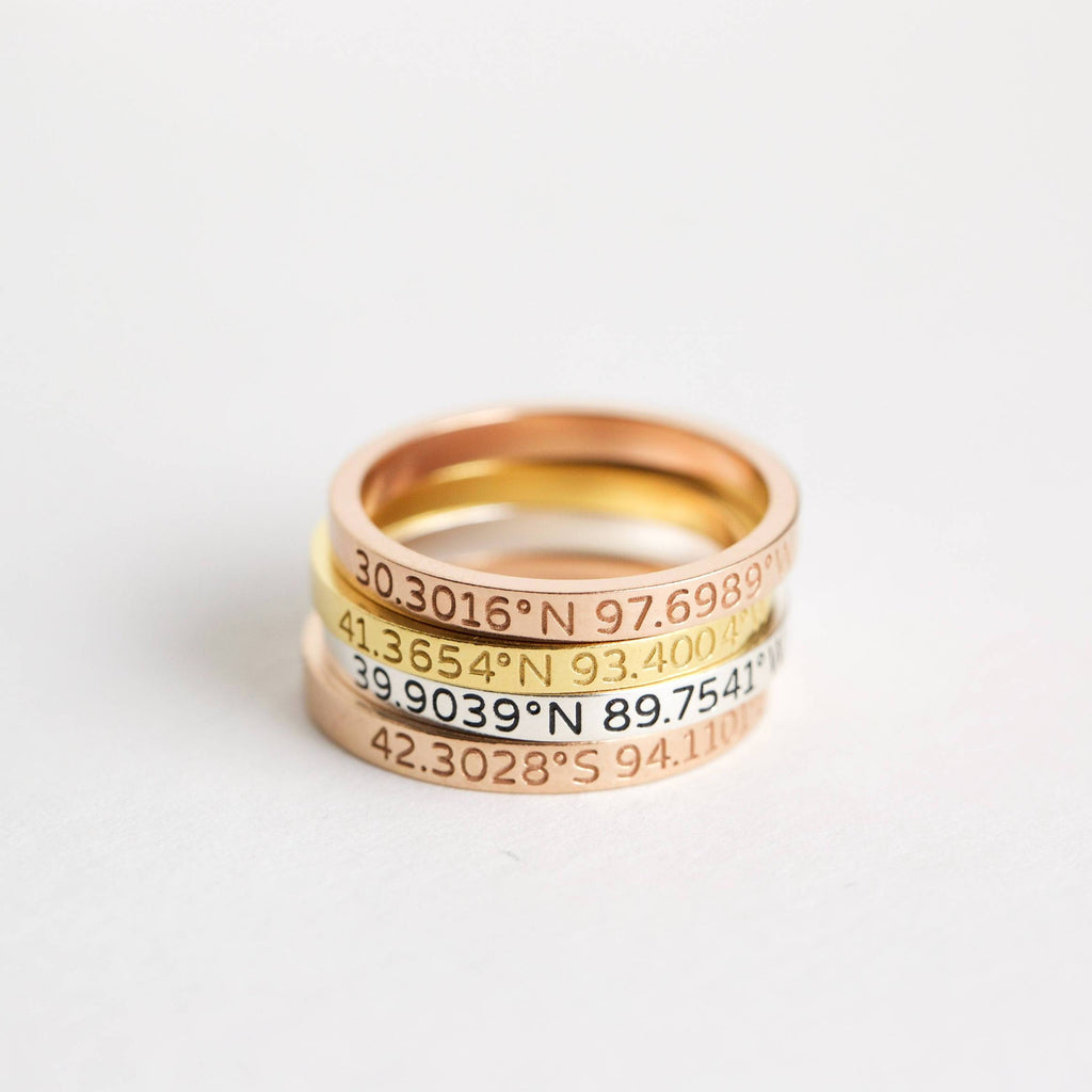 Three stacked metal bands in gold, silver, and rose gold—each a Coordinates Band engraved with geographic coordinates—create a meaningful memory you can wear daily.