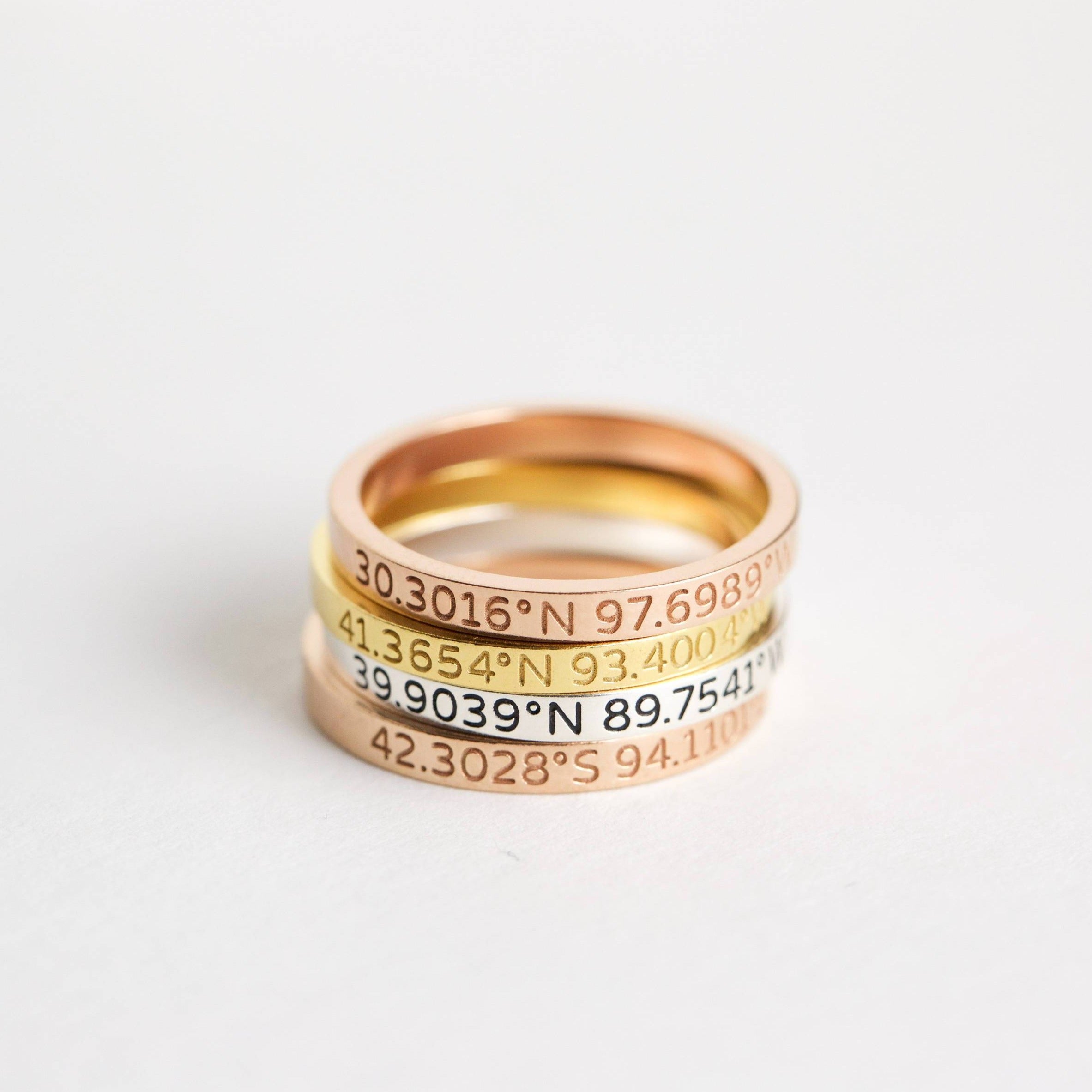 Three stacked metal bands in gold, silver, and rose gold—each a Coordinates Band engraved with geographic coordinates—create a meaningful memory you can wear daily.