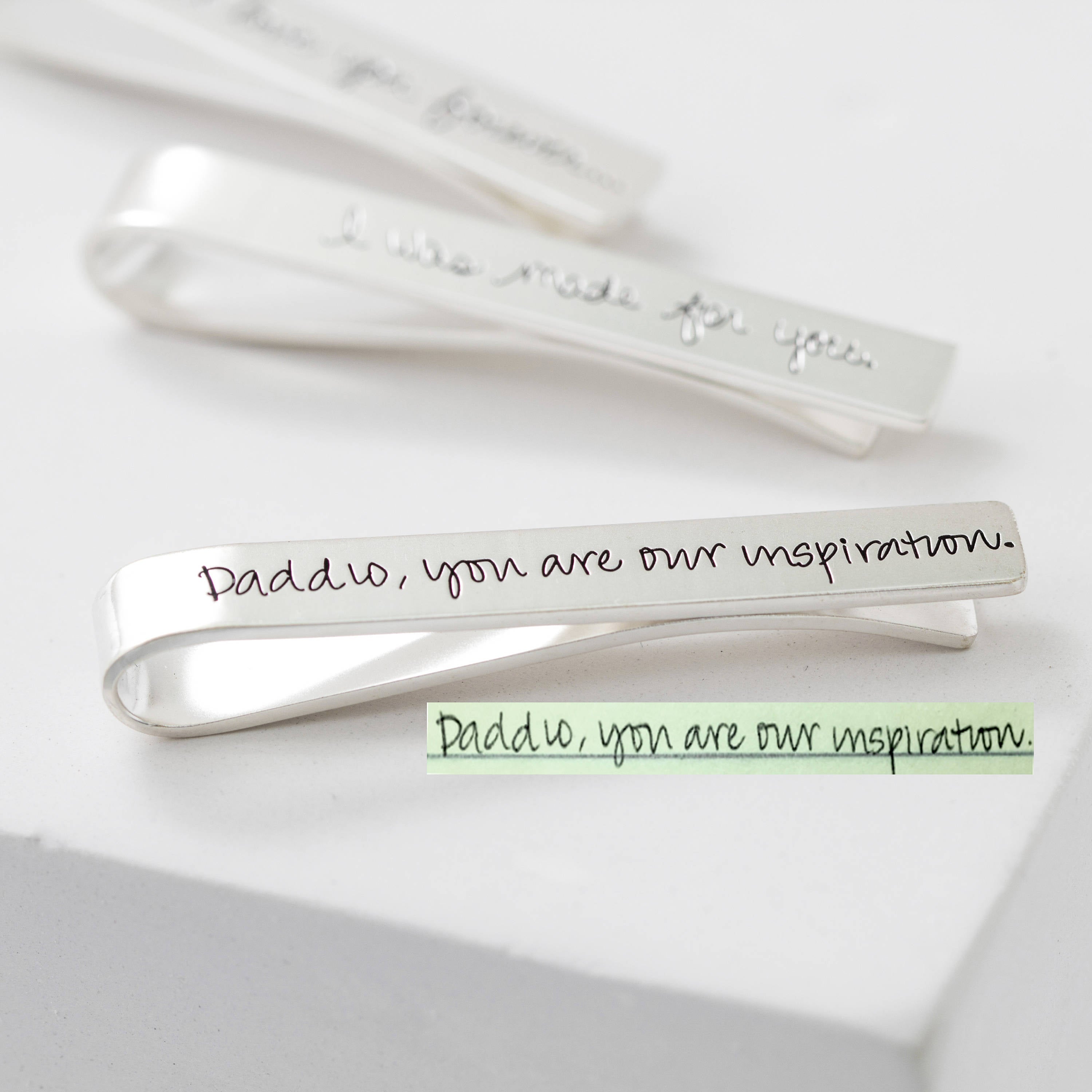 A silver Handwriting Tie Clip engraved with "Daddio, you are our inspiration."—a memorable personalized gift.