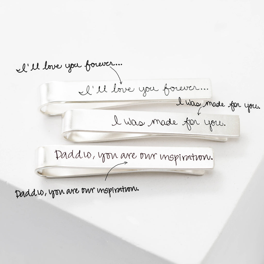 Three silver Handwriting Tie Clips, each engraved with a unique handwritten message: "I'll love you forever...", "I was made for you.", and "Daddy, you are our inspiration." The perfect personalized gift for any occasion.