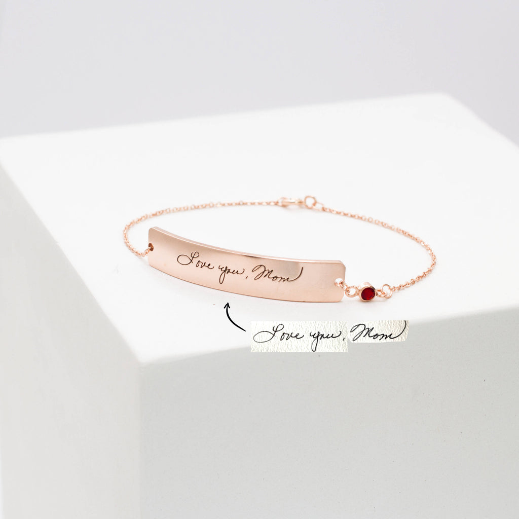 The Handwriting Bar Bracelet in rose gold, engraved with "Love you, Mom" and shown beside a handwritten note, is the perfect personalized jewelry for a heartfelt gift.