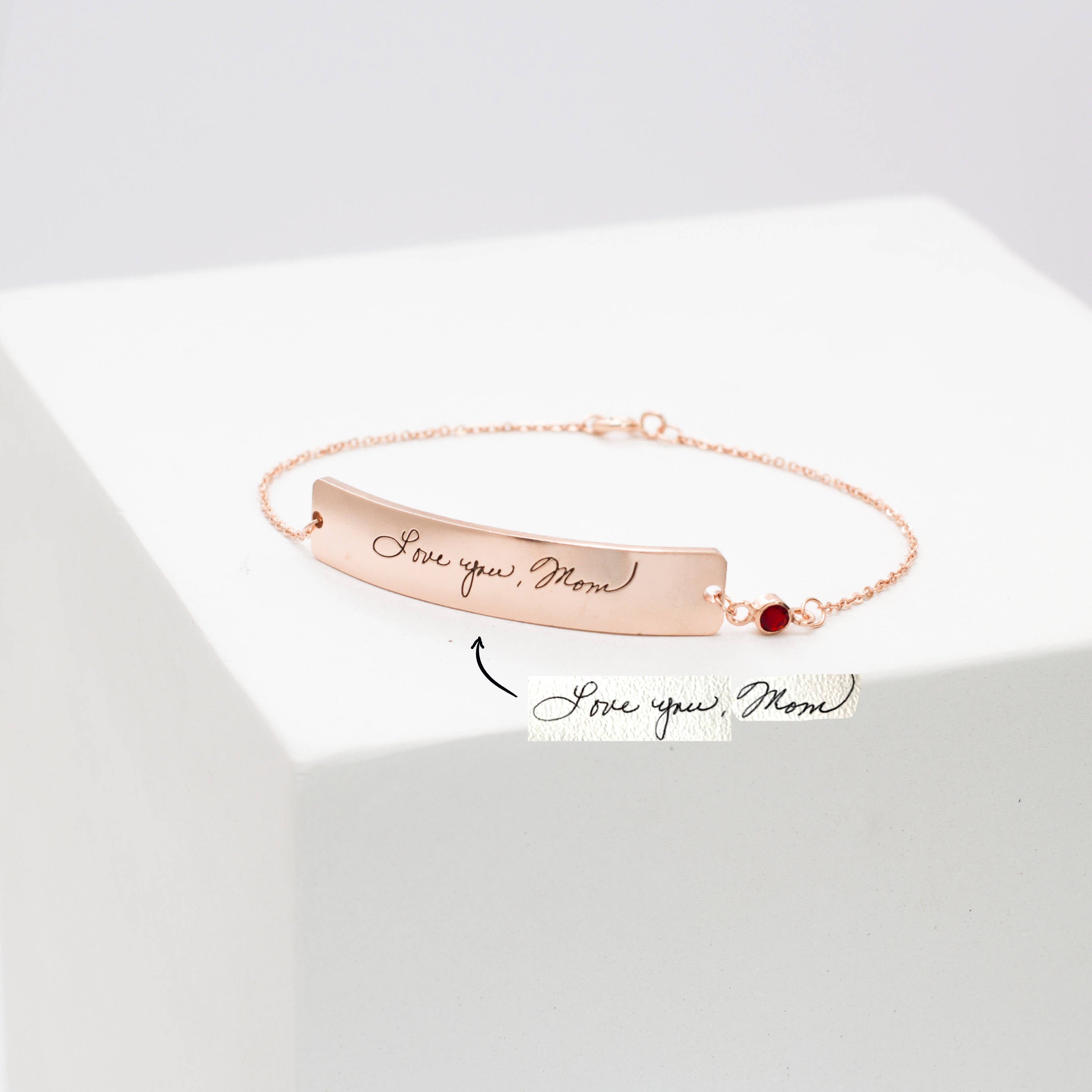 The Handwriting Bar Bracelet in rose gold, engraved with "Love you, Mom" and shown beside a handwritten note, is the perfect personalized jewelry for a heartfelt gift.