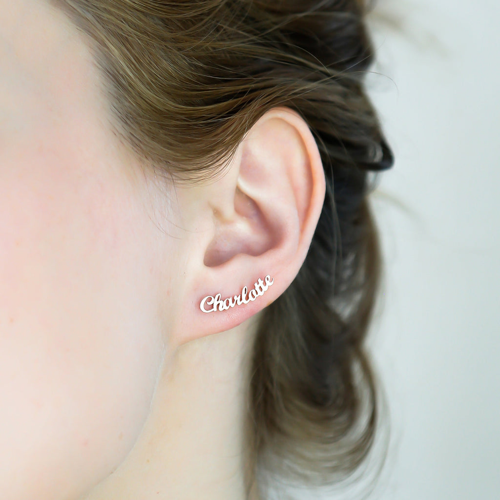 Close-up of an ear wearing a London Name Earring shaped like the word "Charlotte" in elegant gold script font.
