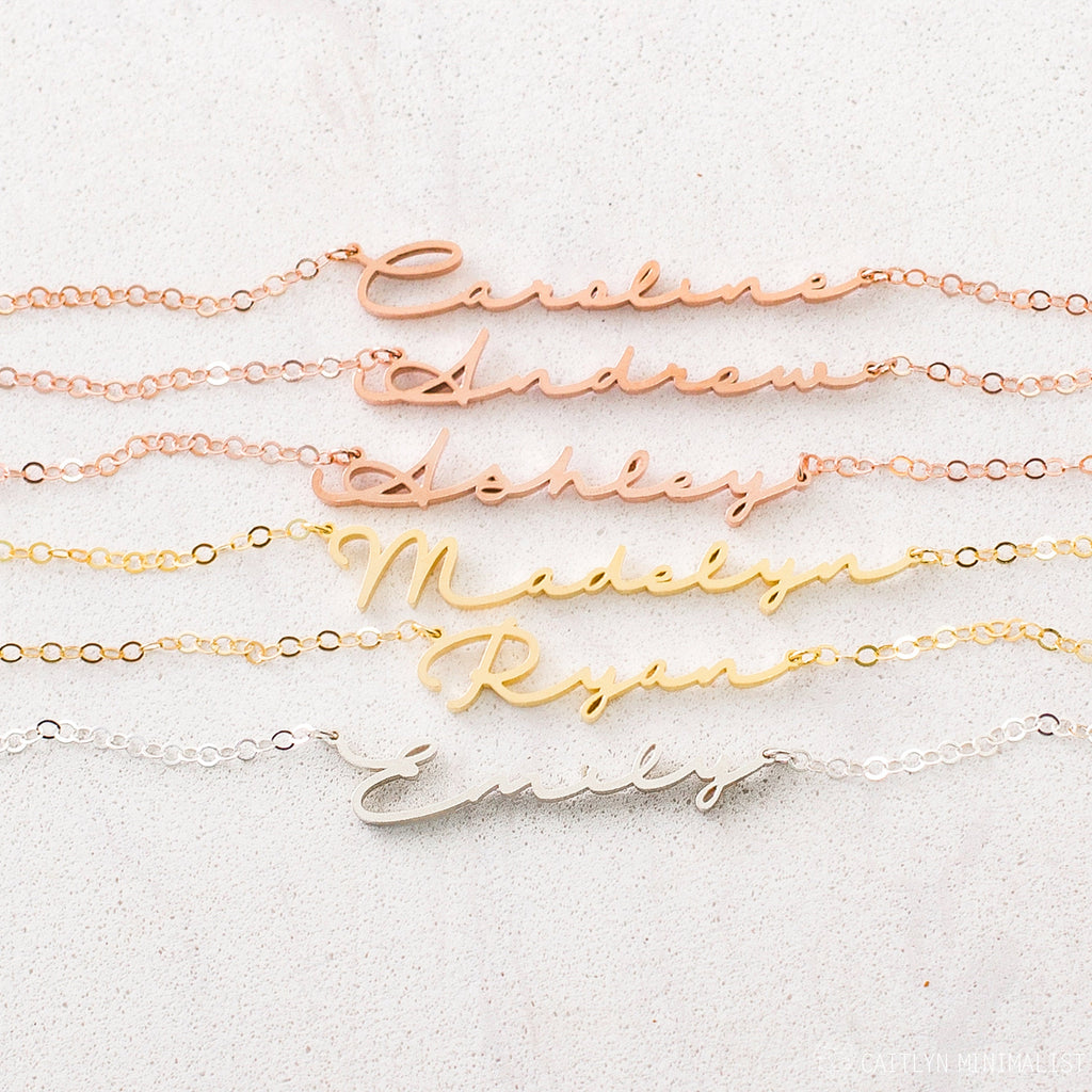The Minimal Name Necklace features delicate chains with names—Caroline, Andrew, Ashley, Madelyn, Ryan, and Emily in script—perfect for lovers of personalized dainty jewelry.