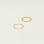 The Bold Stacking Ring Set features two minimal gold rings—one smooth and one with a modern twisted rope design—shown on a plain light background.