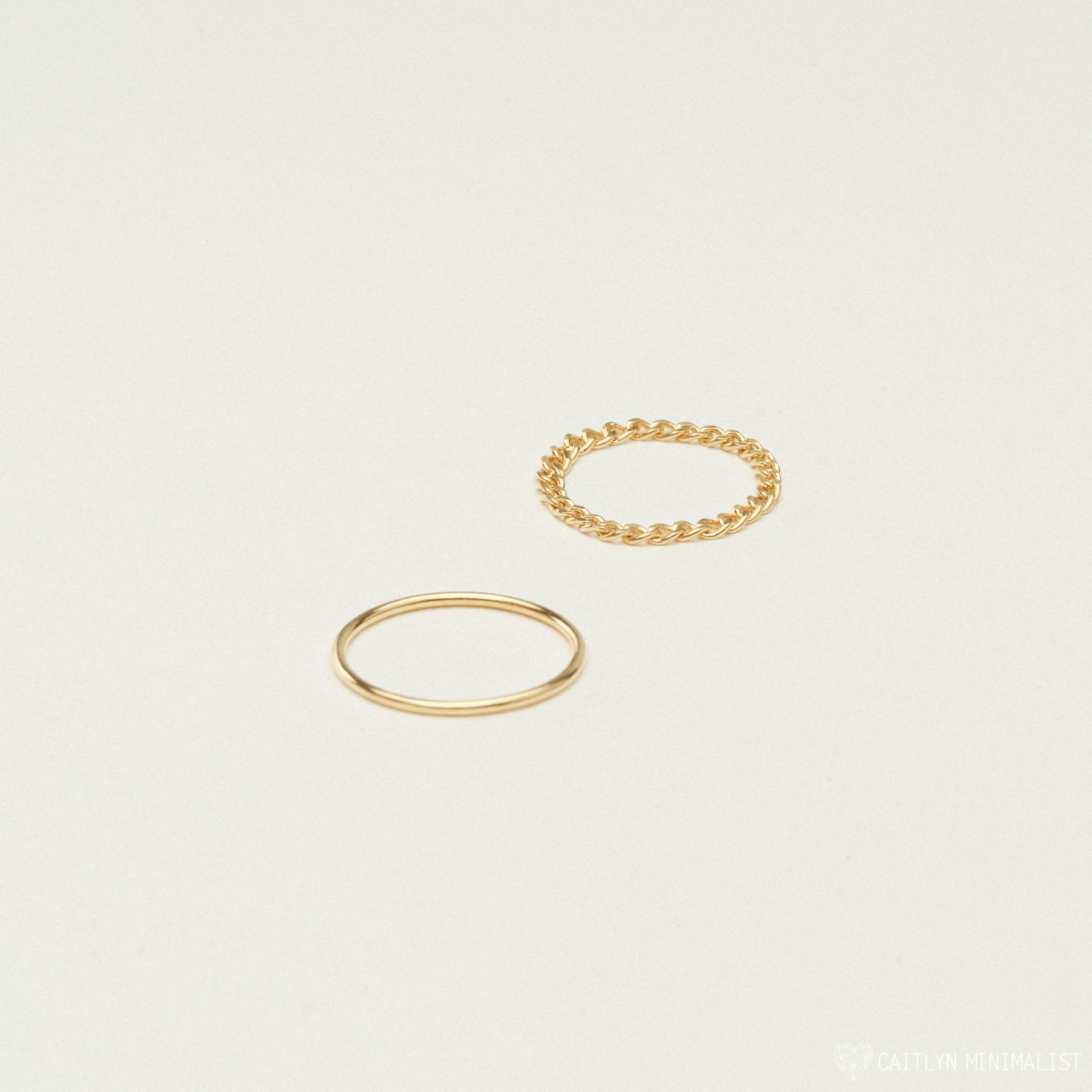 The Bold Stacking Ring Set features two minimal gold rings—one smooth and one with a modern twisted rope design—shown on a plain light background.