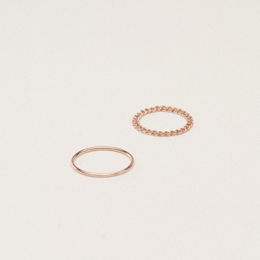 The Bold Stacking Ring Set features two modern, minimal gold rings—one with a smooth band and one with a twisted rope design—displayed on a simple light background.