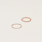 The Bold Stacking Ring Set features two modern, minimal gold rings—one with a smooth band and one with a twisted rope design—displayed on a simple light background.