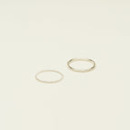 The Minimalist Stacking Ring Set features two silver rings—one twisted, one smooth—creating an elegant, minimalist look on a plain light background.