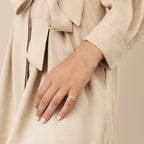 A hand wearing the modern Figaro Bracelet rests on a beige dress with a fabric tie at the waist.