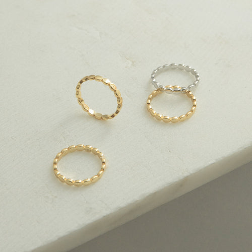 The Beaded Ring, with its textured design in gold and silver tones, is displayed on a light surface—ideal for stacking or wearing solo as a unique piece in your jewelry collection.