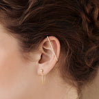 Close-up of an ear wearing gold hoops, a stud, and Bar Ear Cuffs adorned with small pavé gems.