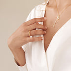Woman in a white blouse wearing the Twisted Dome Ring and a gold necklace with a delicate script pendant.