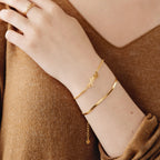 A woman in a brown V-neck top wears a contemporary Herringbone Bracelet and a stylish ring.