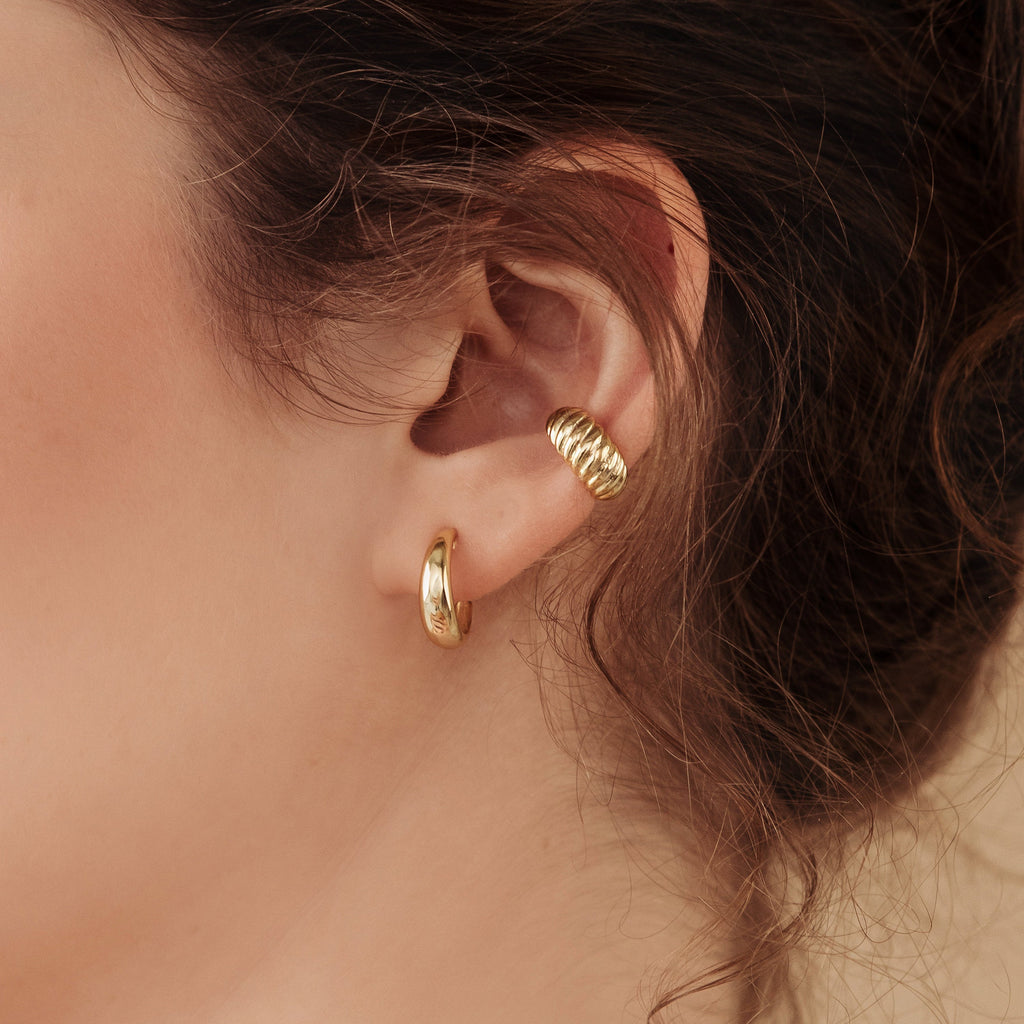 Close-up of a woman's ear wearing Dome Hoops—one classic hoop on the lobe and a chic ear cuff on the upper ear.