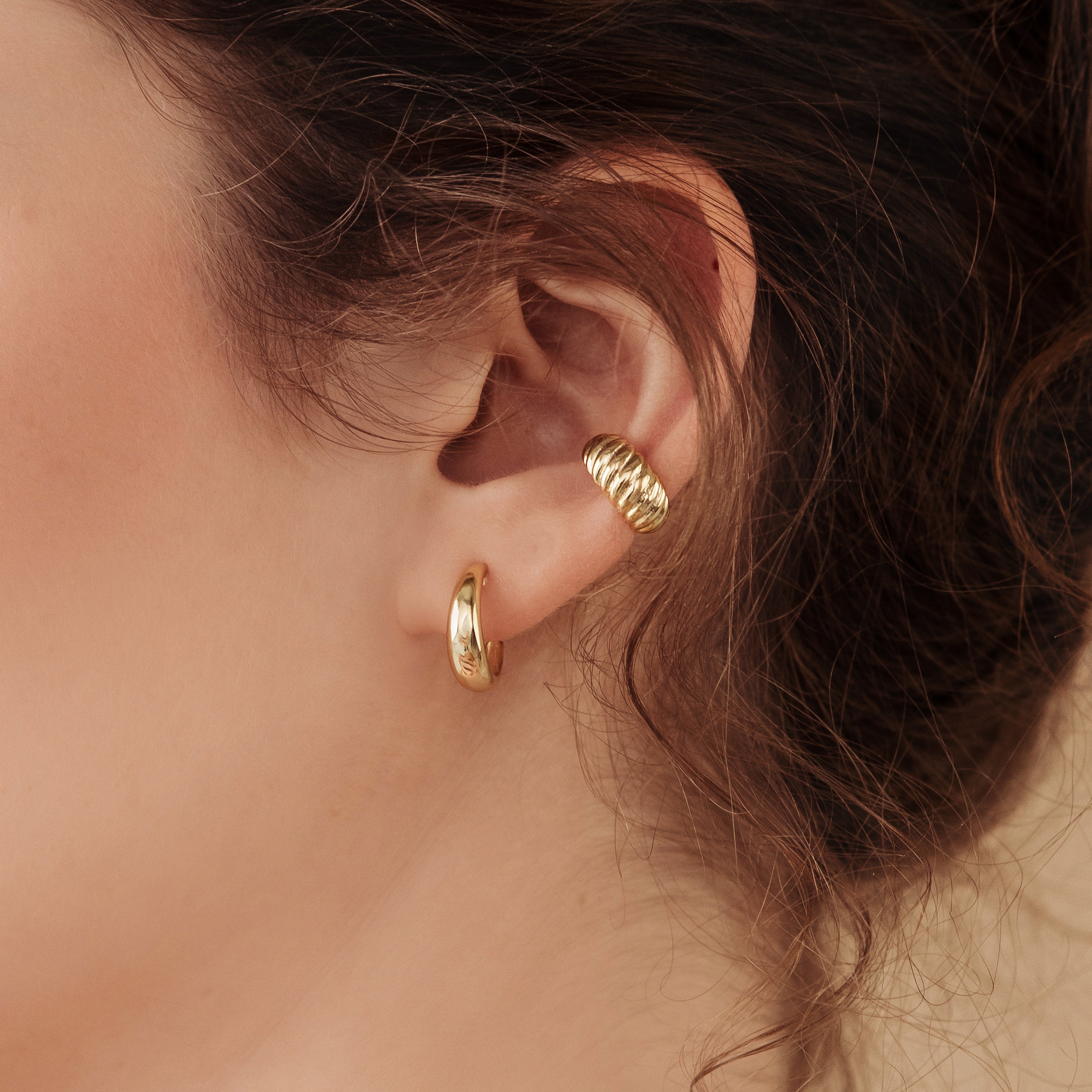 Close-up of a woman's ear wearing Dome Hoops—one classic hoop on the lobe and a chic ear cuff on the upper ear.