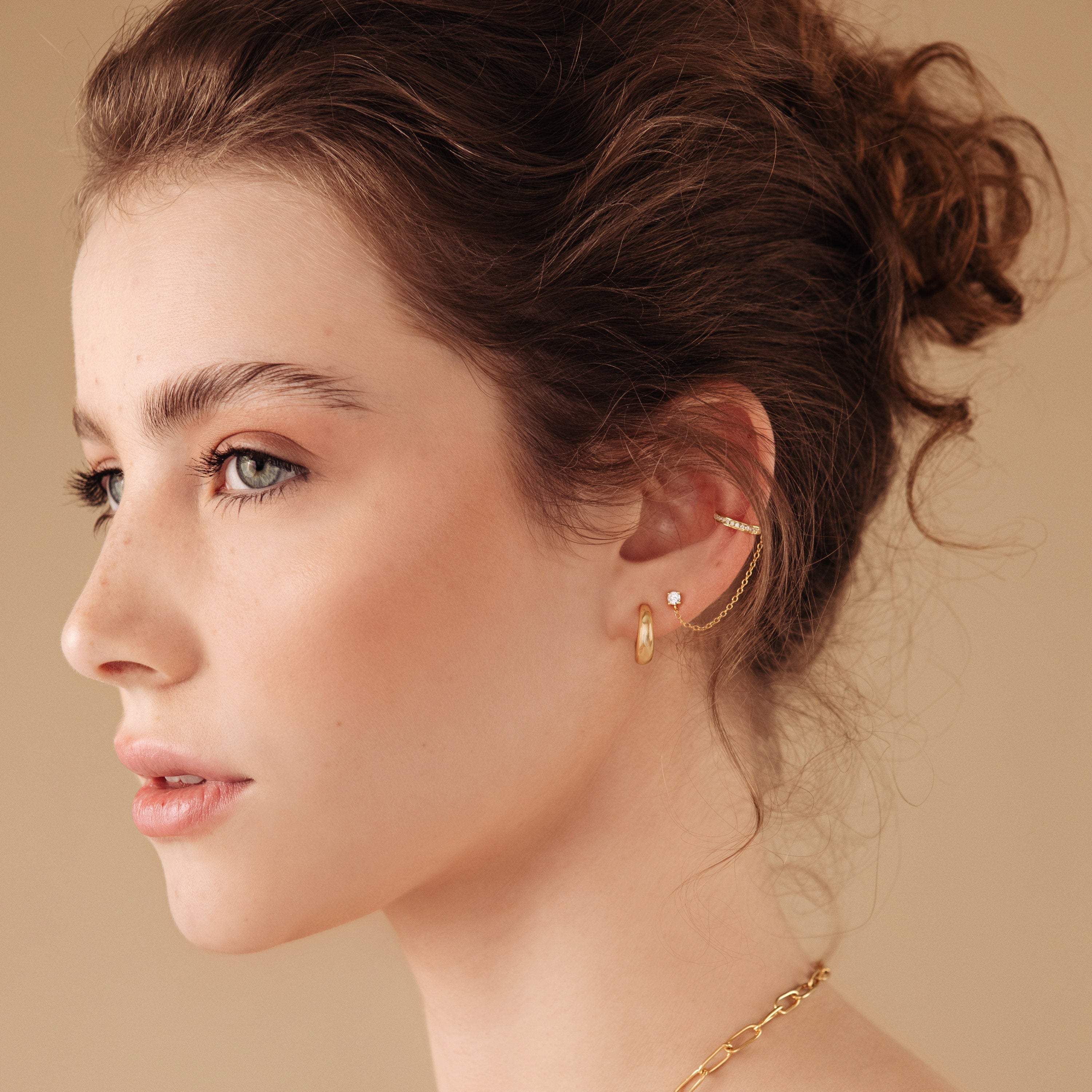A woman with a hair bun wears Dome Hoops earrings.