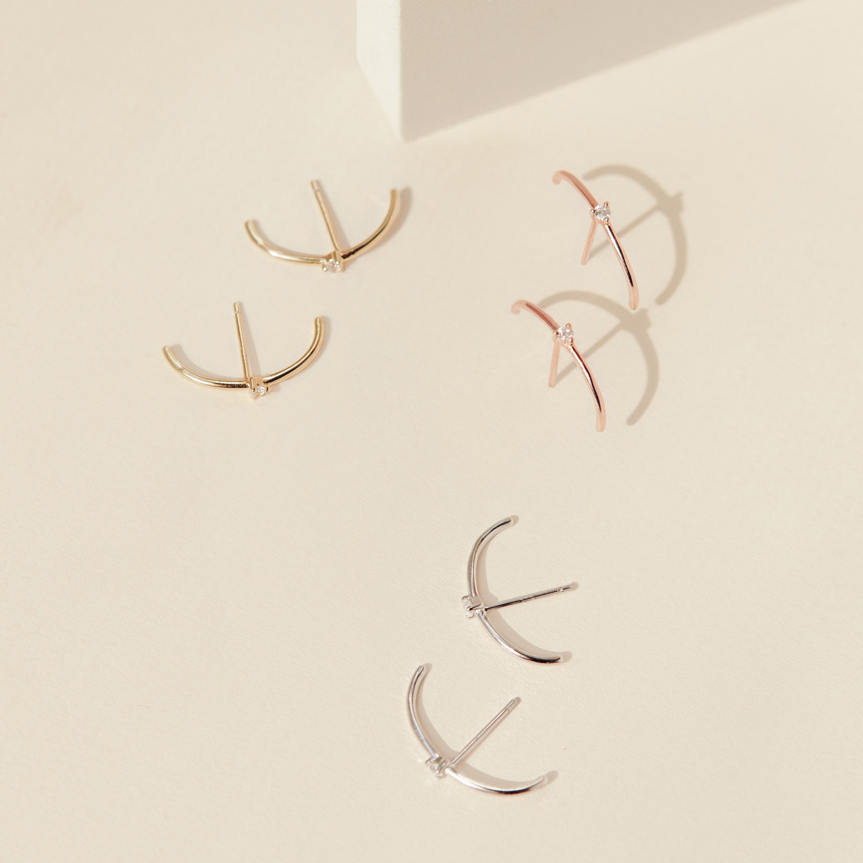 Arc Studs: A set of three pairs of minimalist arc-shaped earrings in gold, rose gold, and silver—ideal for fans of simple ear jewelry.