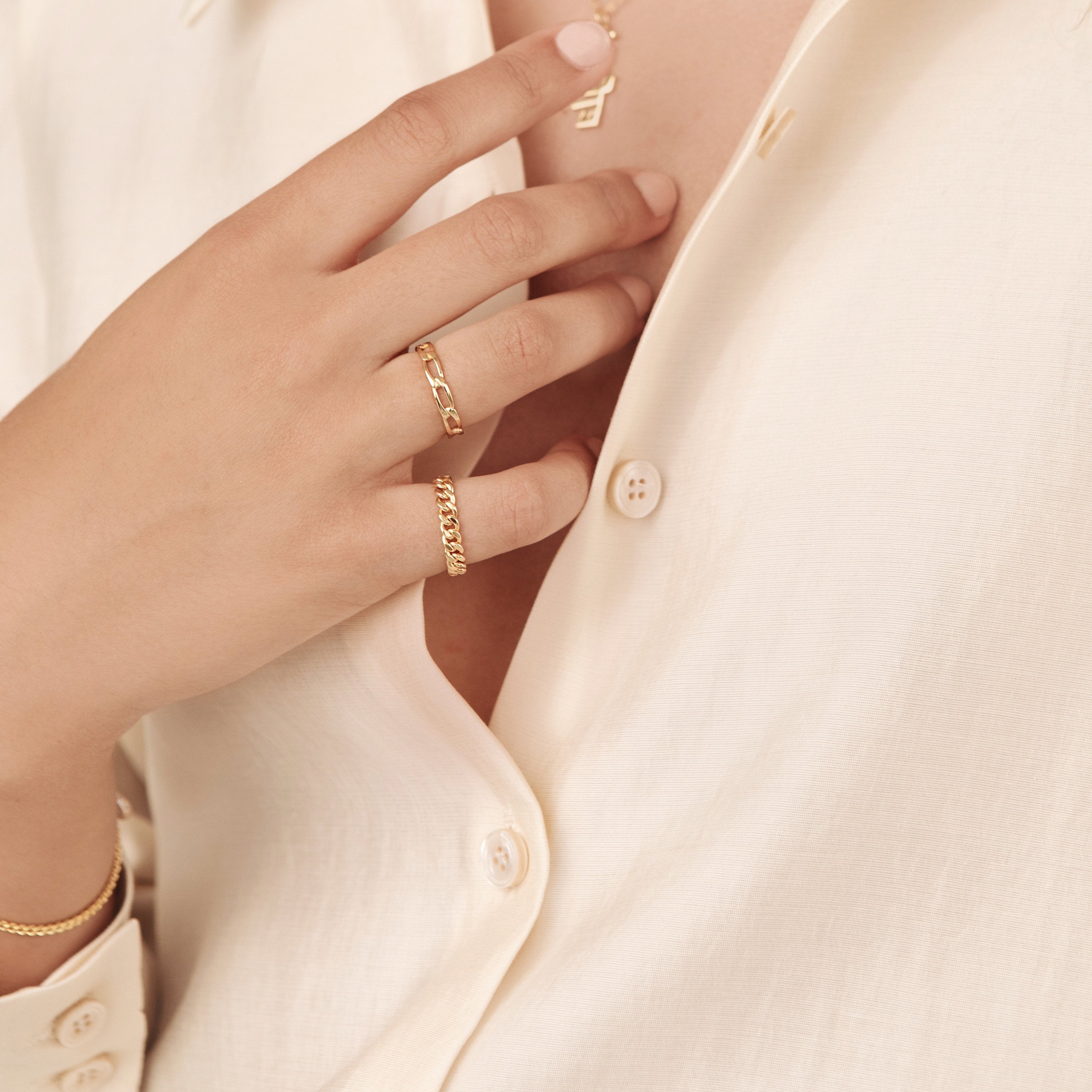 Close-up of model’s hand adjusting clothing, with the link ring visible to showcase its wearability and subtle shine.