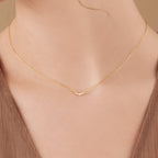 Close-up of a woman's neck wearing the Lucia Pave Necklace, a delicate gold piece featuring a small crescent charm pendant.