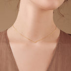 Close-up of a woman's neck wearing the Lucia Pave Necklace, featuring a delicate gold chain with a small crescent charm.