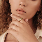 Close-up of a woman wearing the gold Dome Ring on her index finger, styled with a gold necklace and soft makeup for a chic, modern look.