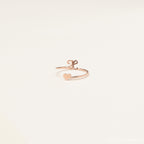 The Initial Heart Wrap Ring showcases a rose gold heart on one end and a customizable lowercase initial "e" on the other—a delicate, personalized symbol of love set against a plain background.