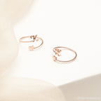 Two delicate Initial Heart Wrap Rings in rose gold, customized with your chosen initials and heart charms—a perfect symbol of love—displayed on a soft cream background.