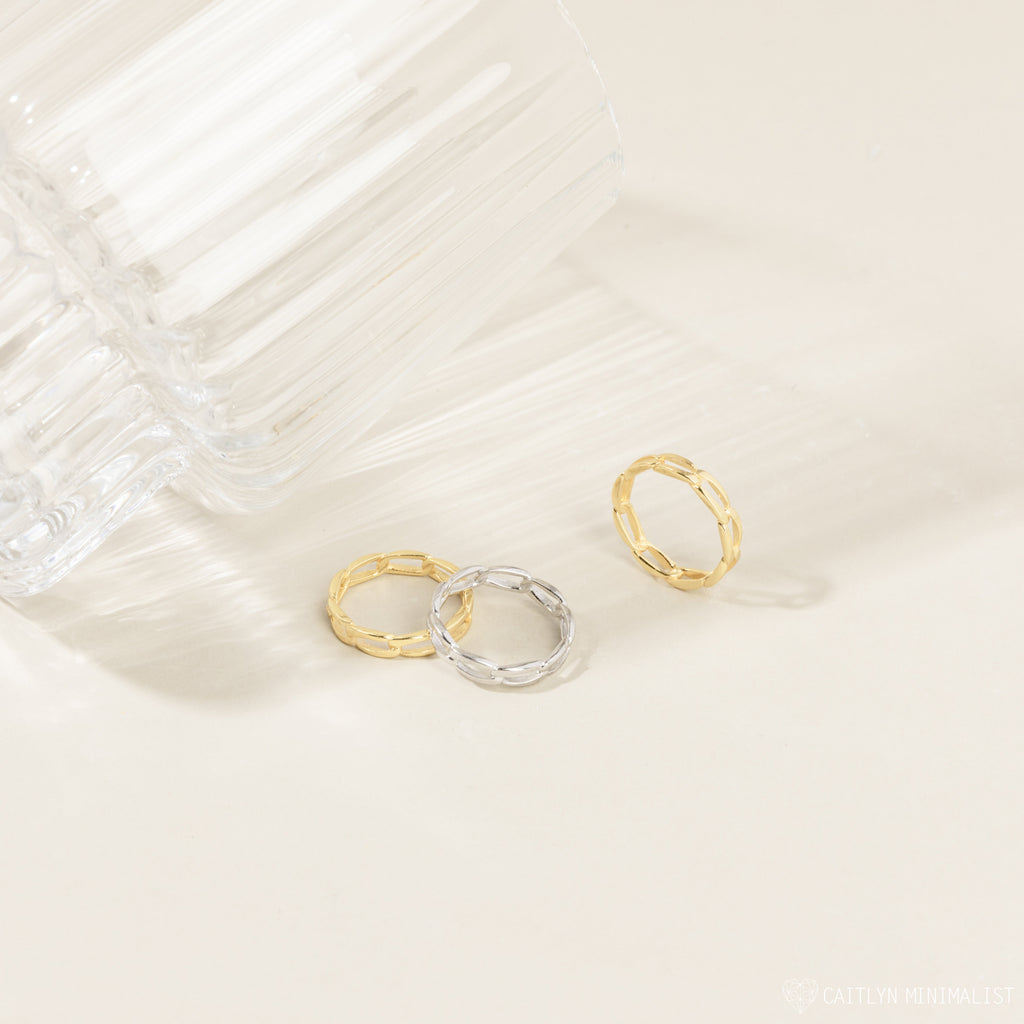 Pair of the gold and silver link rings placed closely together on a fabric backdrop, highlighting the linked design and contrast in finish.