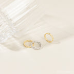 Pair of the gold and silver link rings placed closely together on a fabric backdrop, highlighting the linked design and contrast in finish.