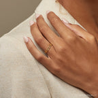 Close-up of a woman’s hand resting on her shoulder, wearing the delicate 3 mm link ring in 18K gold.