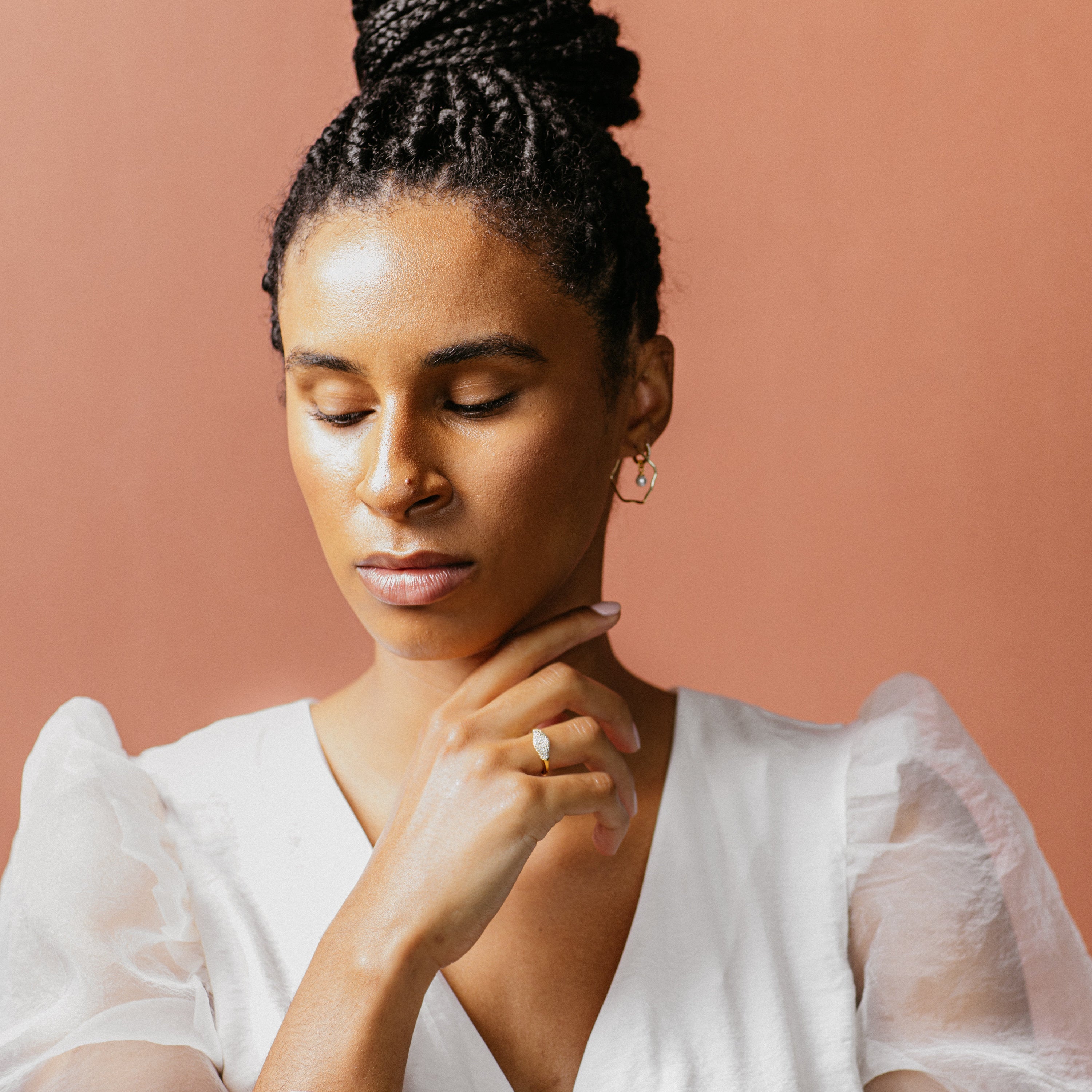 A woman with her hand on her chin highlights a modern-luxe look, featuring the Pave Signet Ring as her statement accessory.