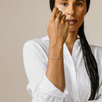 Woman in a white shirt wears the Pave Mama Script Bracelet on her wrist, celebrating the elegance of mama jewelry.