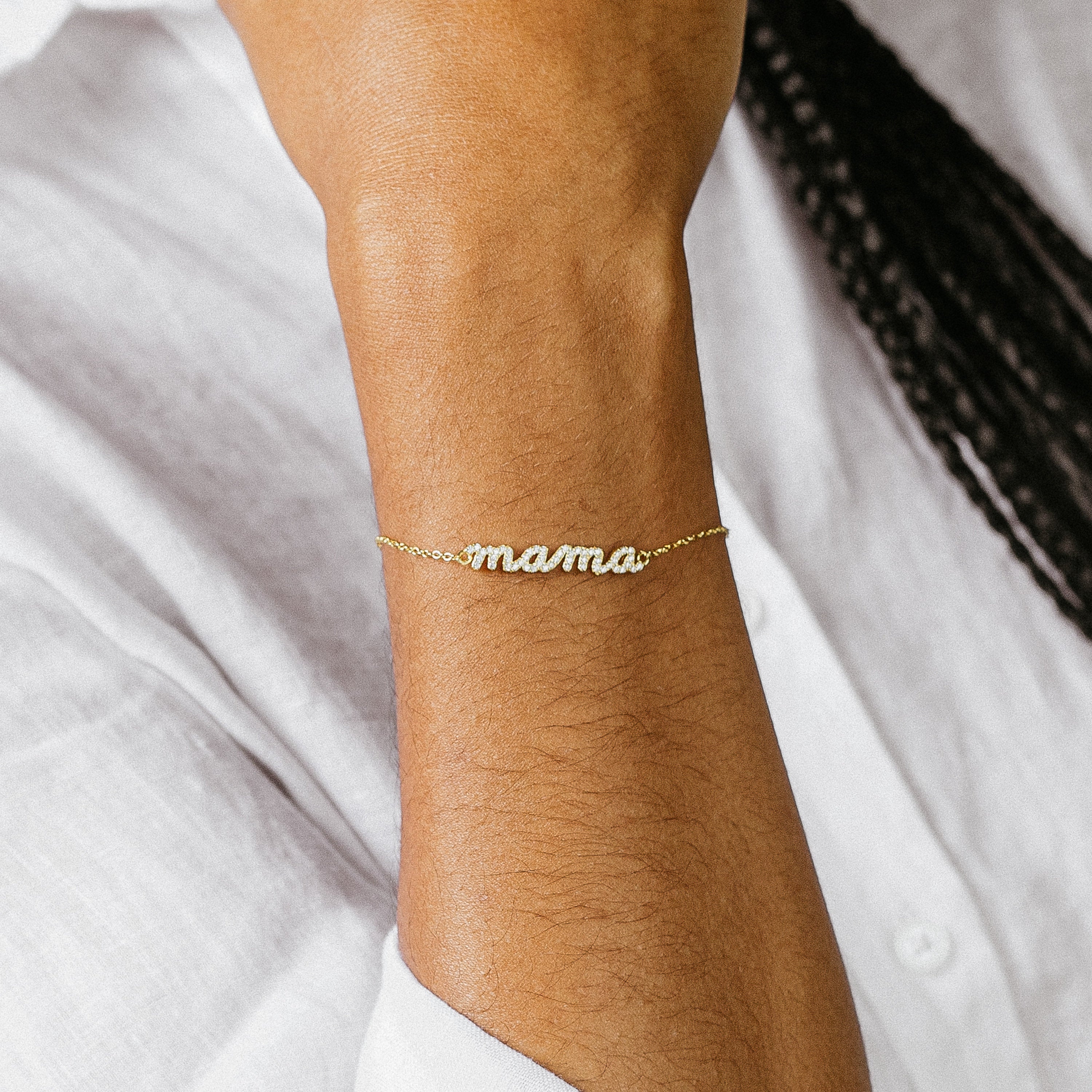 The Pave Mama Script Bracelet sparkles on the wrist, styled with a classic white shirt—a chic piece of mama jewelry that honors motherhood with timeless elegance.